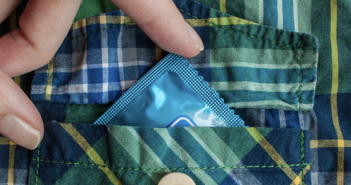 Mão feminina colocando camisinha dentro de bolso de camisa