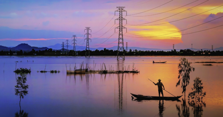 Pessoa remando uma canoa ao pôr do sol, torres de energia ao fundo.