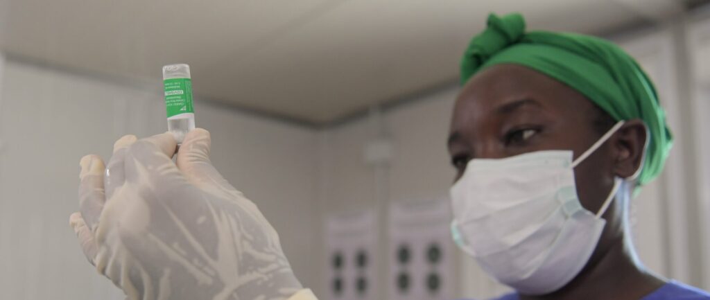 Fotografía en color de un trabajador de la salud negro en Somalia que prepara una jeringa con una dosis de la vacuna covid-19.