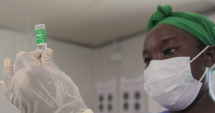 Fotografía en color de un trabajador de la salud negro en Somalia que prepara una jeringa con una dosis de la vacuna covid-19.