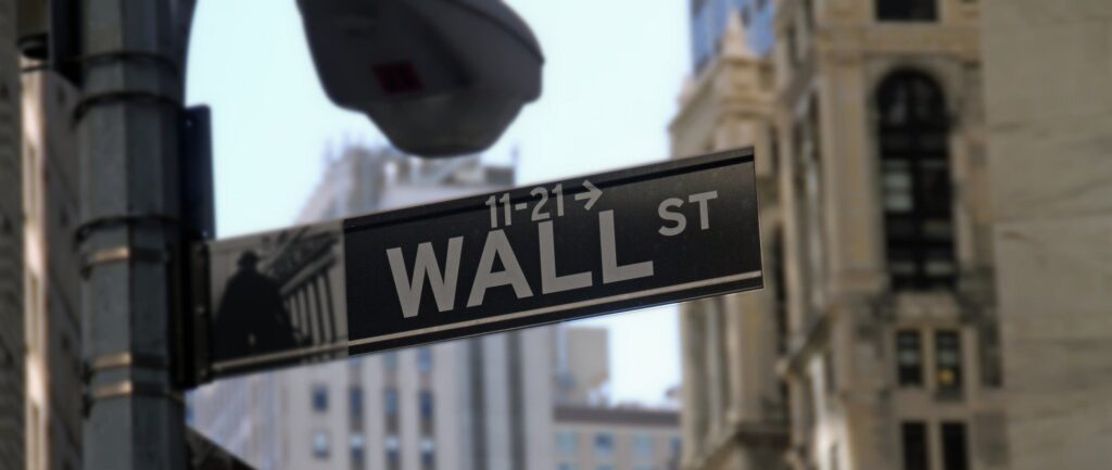 Fotografia em cores de placa de rua em Nova Iorque, indicando Wall Street.