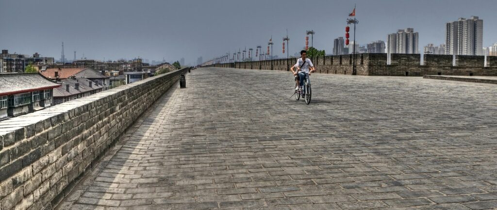 Fotografia em cores de cidade de Xi'an vazia exceto por duas pessoas em uma bicicleta.