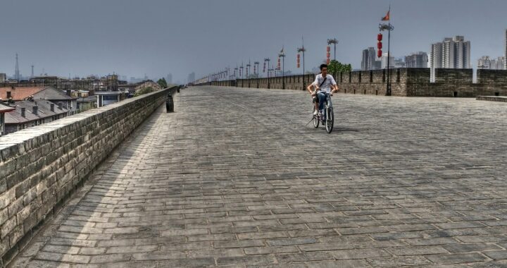 Fotografia em cores de cidade de Xi'an vazia exceto por duas pessoas em uma bicicleta.
