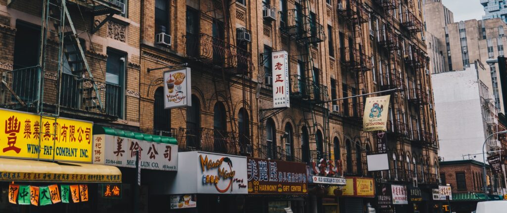 Fotografia em cores mostrando fachada de prédios e lojas na Chinatown de Nova Iorque, Estados Unidos,