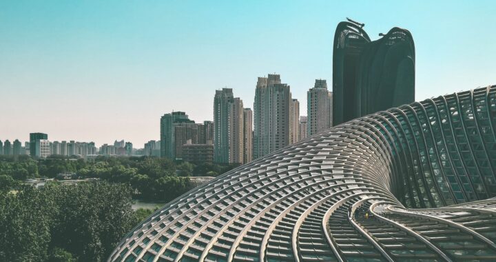 Fotografia em cores com leve filtro amarelado. Em primeiro plano, o prédio do Phoenix International Media Center. Ao fundo, o restante da cidade e um prédio com guindastes ainda em uso.