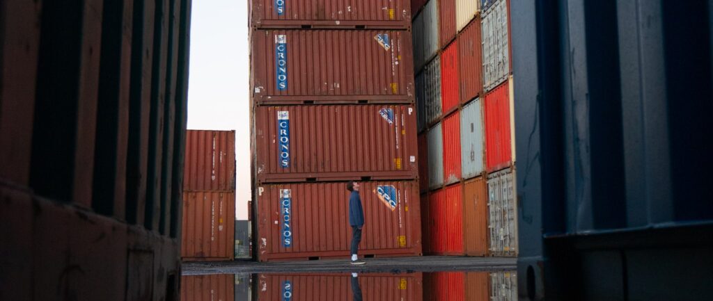 Fotografía en color de un hombre mirando una pila de coloridos contenedores de exportación