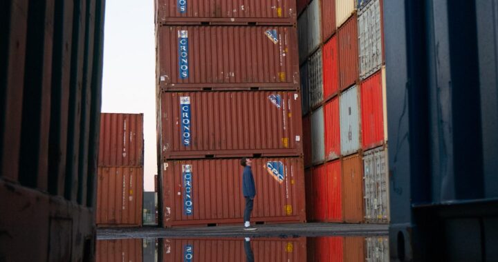 Fotografía en color de un hombre mirando una pila de coloridos contenedores de exportación