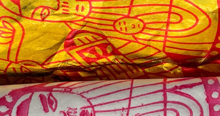 Fotografía en color del papel de incienso utilizado como ofrenda al difunto. Uno de ellos es blanco, el otro es amarillo, ambos tienen diseños rojos. Los dibujos son de entidades masculinas.