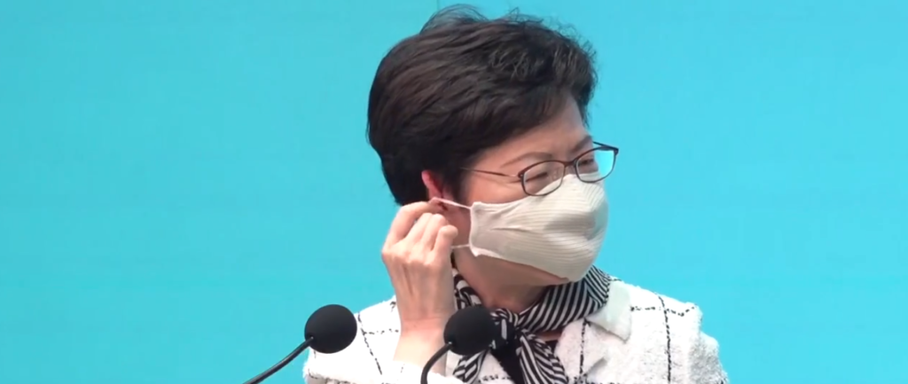 Fotografía de la directora ejecutiva de Hong Kong, Carrie Lam, quitándose una máscara facial de tela durante una conferencia de prensa.