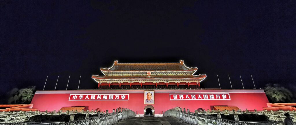 Fotografia em cores da Porta de Tiananmen iluminada à noite.