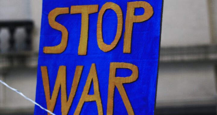 Fotografia em cores de cartaz em azul, com as palavras STOP WAR (pare a guerra) escritas em amarelo.