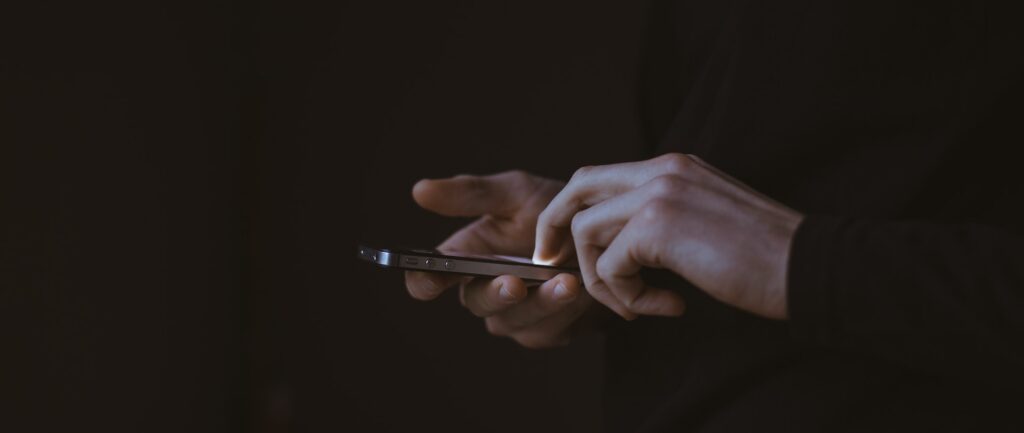 Fotografia em cores de mãos manipulando um celular.