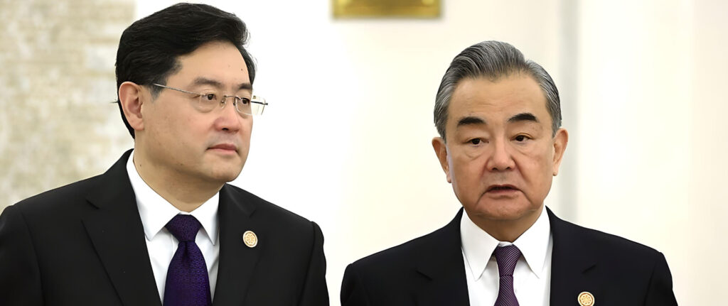 Fotografia em cores de Qin Gang e Wang Yi lado a lado em cerimônia oficial.