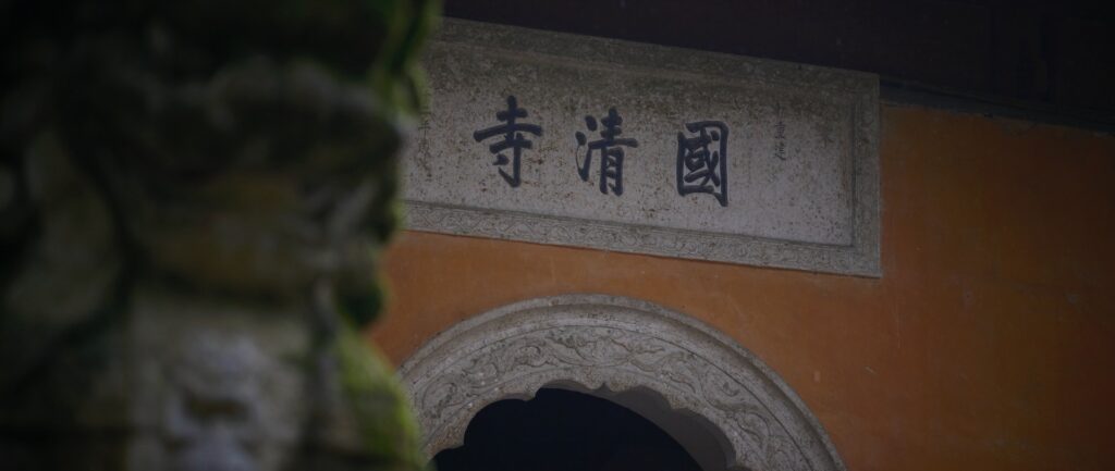 ALT TEXT: uma estátua de um leão na frente de um edifício de arquitetura chinesa e com caracteres chineses