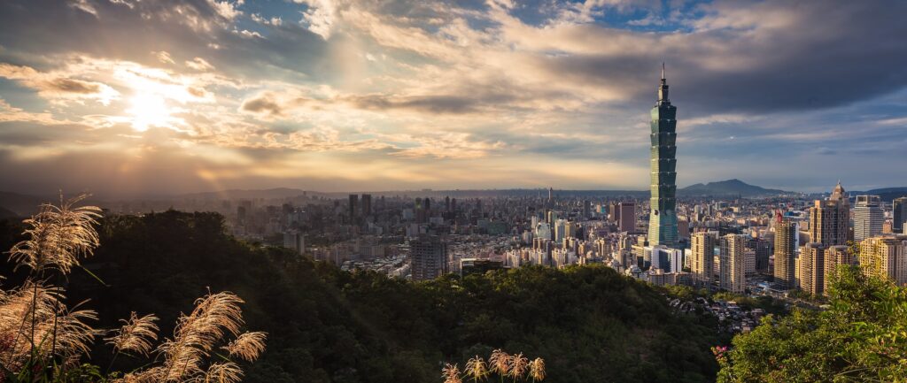 Fotografia panorâmica em cores de Taipei em dia de sol, com destaque para a torre Taipei 101.