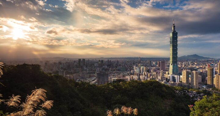 Fotografia panorâmica em cores de Taipei em dia de sol, com destaque para a torre Taipei 101.