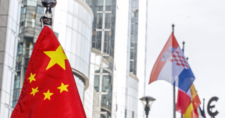 Foto de bandeiras no prédio do Parlamento Europeu, com a bandeira da China em primeiro plano e outras bandeiras europeias e o logo do Euro
