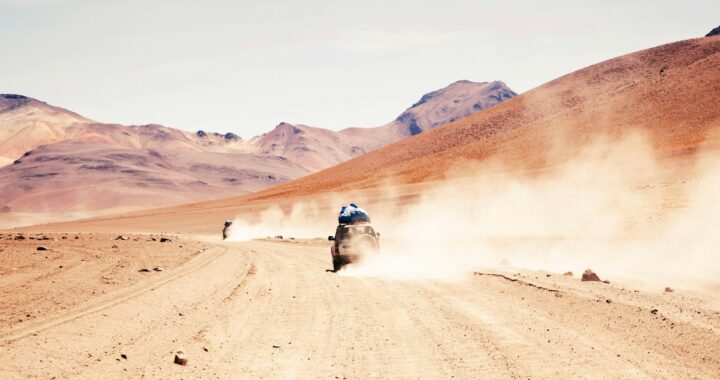 Fotografia em cores de jipe acelerando em deserto na Bolívia.