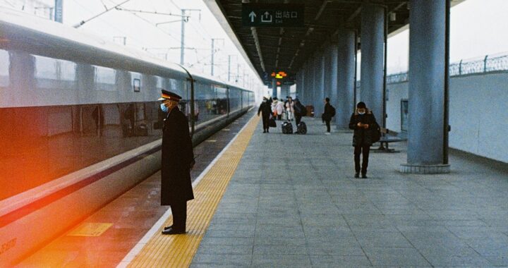 Fotografia em cores de pessoas em plataforma de trem na China, comefeito de luz sobre o trem que parece passar em alta velocidade