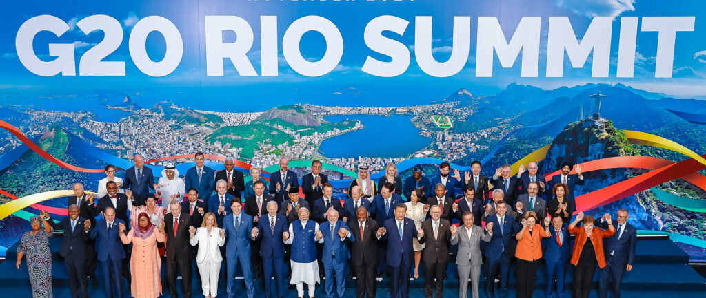 Foto oficial do encontro do G20 no Rio, em cores. Todos os líderes posam de mãos dadas, erguidas para o alto.