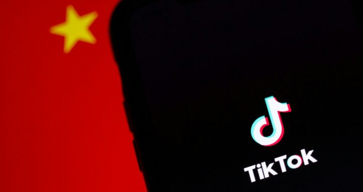 Imagem em cores de celular com o aplicativo TikTok diante de bandeira da China.