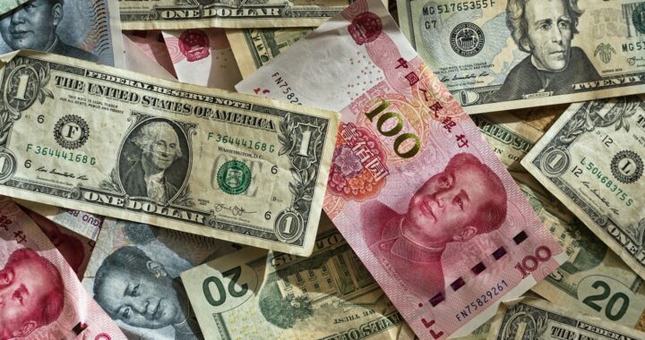 Fotografia em cores de notas de dólar estadunidense e renminbi chinês.