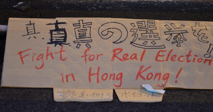 Placa escrita em mandarim e em inglês com a mensagem de lute por eleições democráticas em Hong Kong