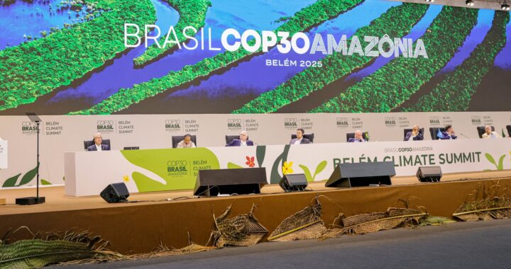 Fotografia da abertura da Plenária da COP30, com uma mesa branca e um painel grande ao fundo dizendo Brasil COP30 Amazônia