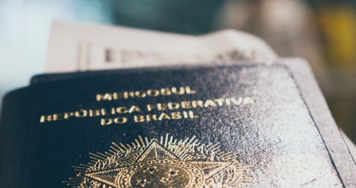 Fotografia em cores de um passaporte brasileiro com um cartão de embarque dentro, fora de foco.
