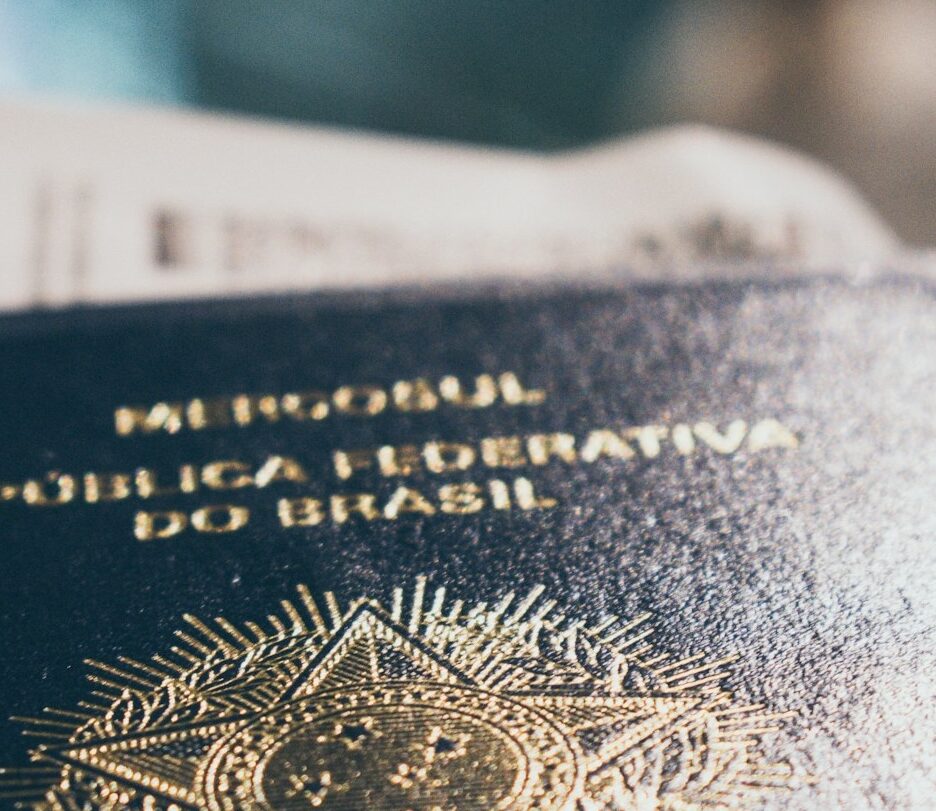 Fotografia em cores de um passaporte brasileiro com um cartão de embarque dentro, fora de foco.