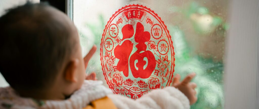 Fotografia em cores de bebê observando decoração de ano novo chinês com caractere de sorte.