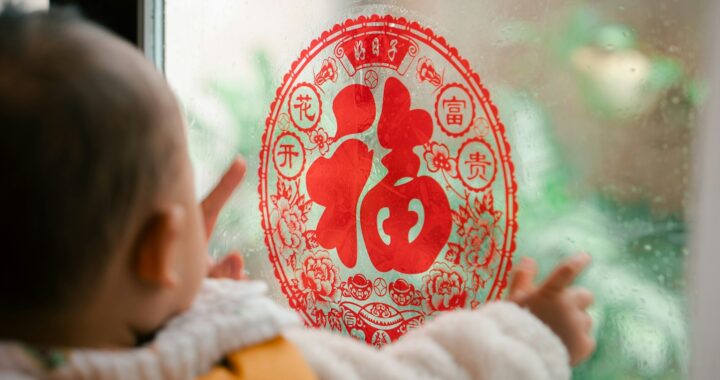 Fotografia em cores de bebê observando decoração de ano novo chinês com caractere de sorte.