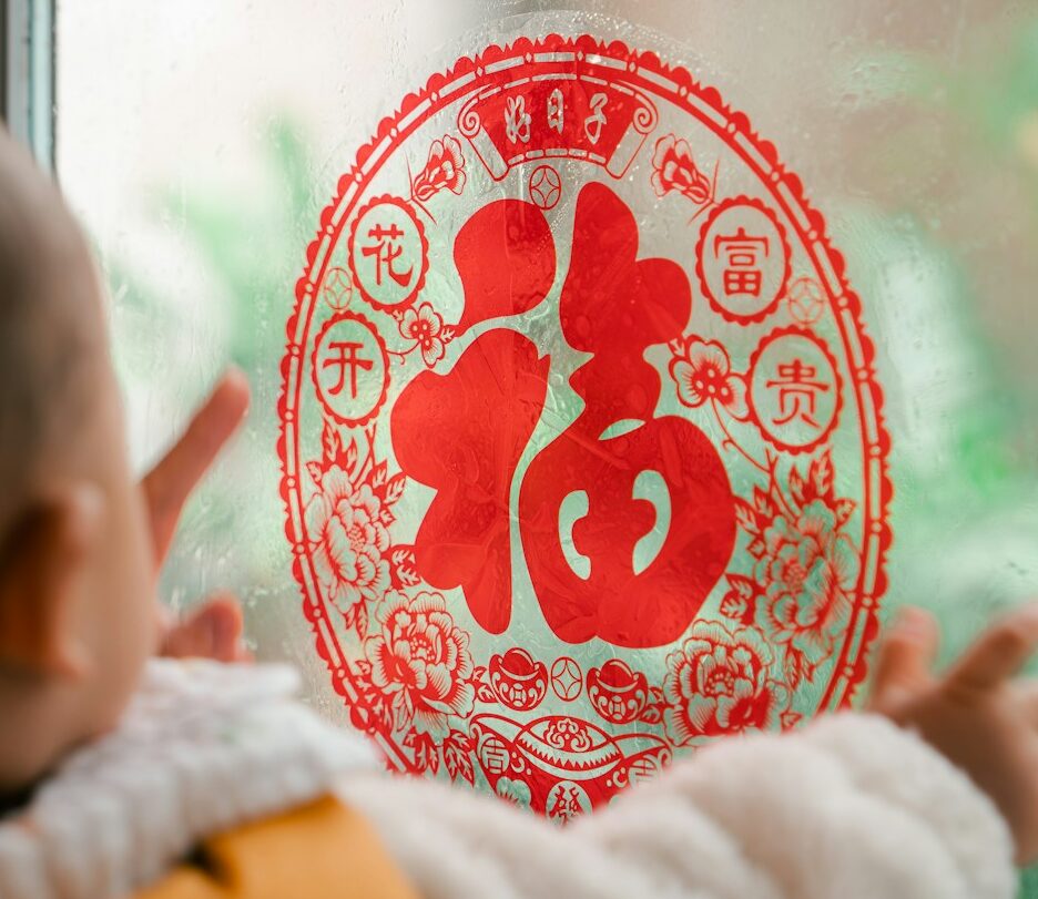 Fotografia em cores de bebê observando decoração de ano novo chinês com caractere de sorte.