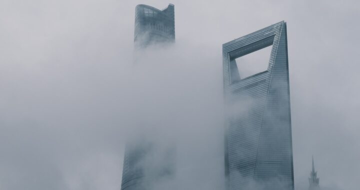 Fotografia em cores de arranha-céus em Shanghai parcialmente encobertos por neblina.