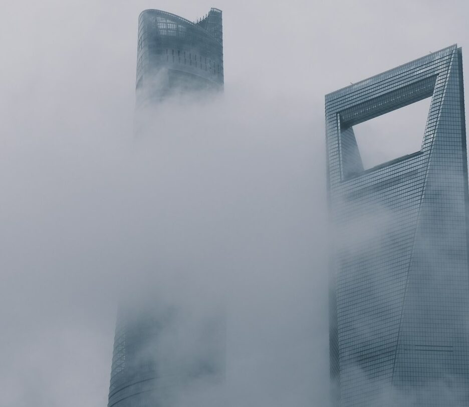Fotografia em cores de arranha-céus em Shanghai parcialmente encobertos por neblina.