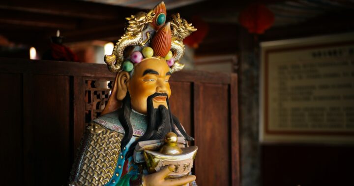 Foto de estátua da deidade taoísta chinesa que atrai fortunas – um homem de cavanhaque, com trajes coloridos, portando um lingote de ouro.