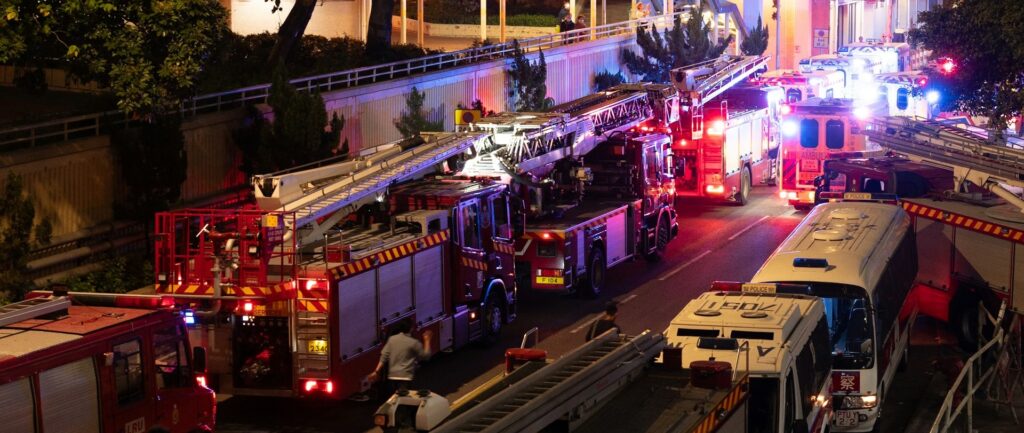 Foto de caminhões de bombeiros e veículos de emergência em frente ao Wang Fuk Court em Hong Kong