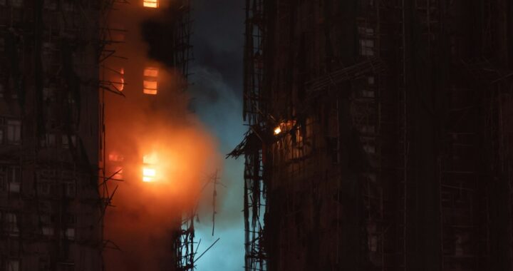 Foto noturna em cores de foco de incêndio em prédio cercado de andaimes.