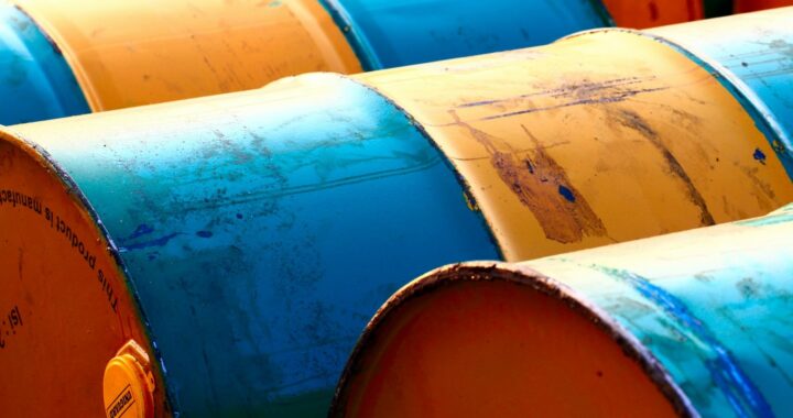Foto em cores de barris azuis e amarelos de petróleo.