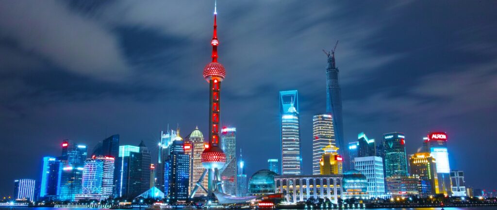 Fotografia em cores de perfil de Shanghai de noite, com os principais prédios da cidade iluminados.