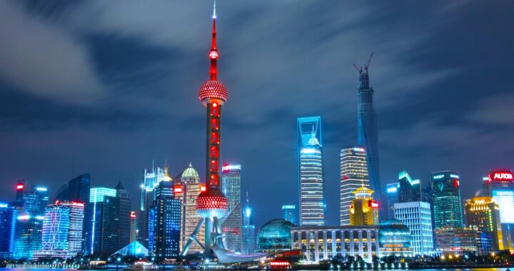 Fotografia em cores de perfil de Shanghai de noite, com os principais prédios da cidade iluminados.