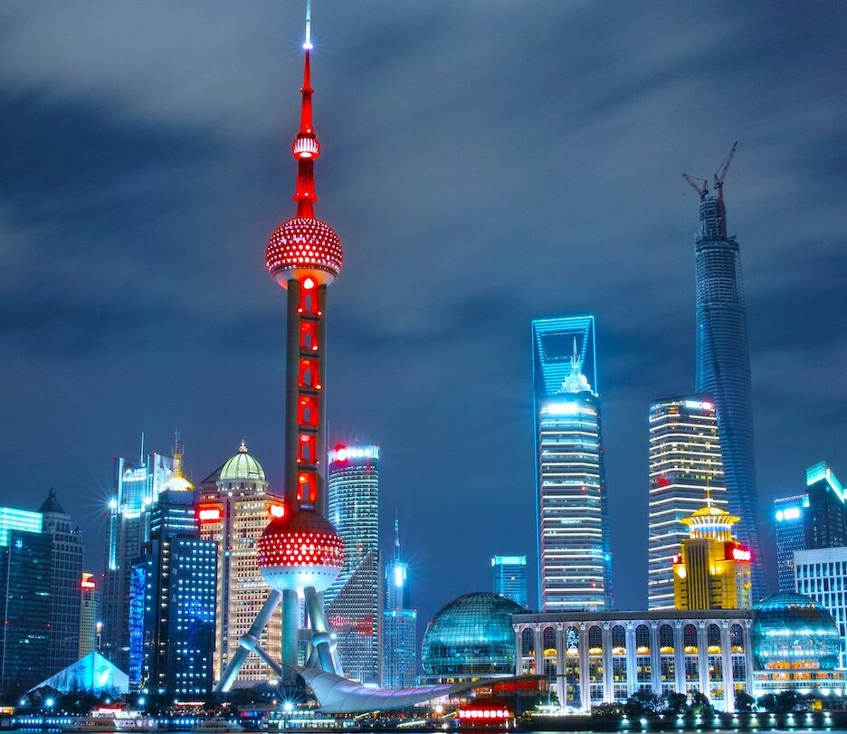 Fotografia em cores de perfil de Shanghai de noite, com os principais prédios da cidade iluminados.