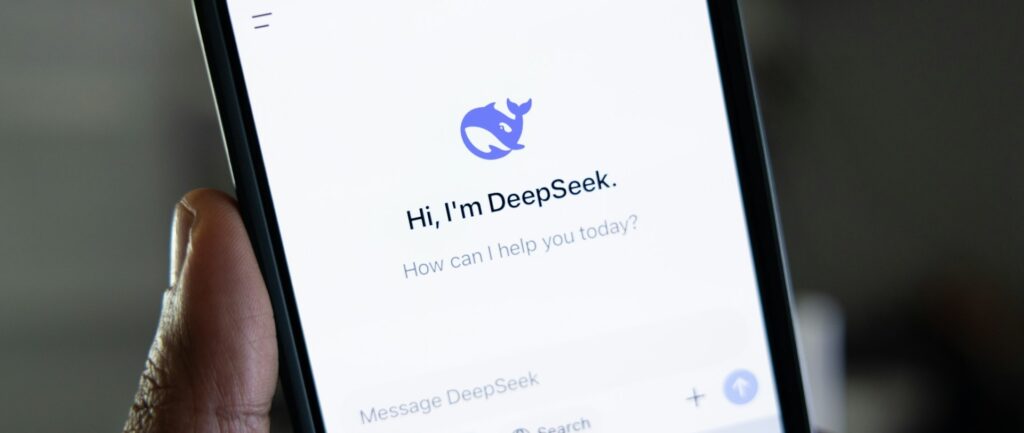 Fotografia em cores de um celular na mão de uma pessoa; o aplicativo aberto no celular é o DeepSeek.