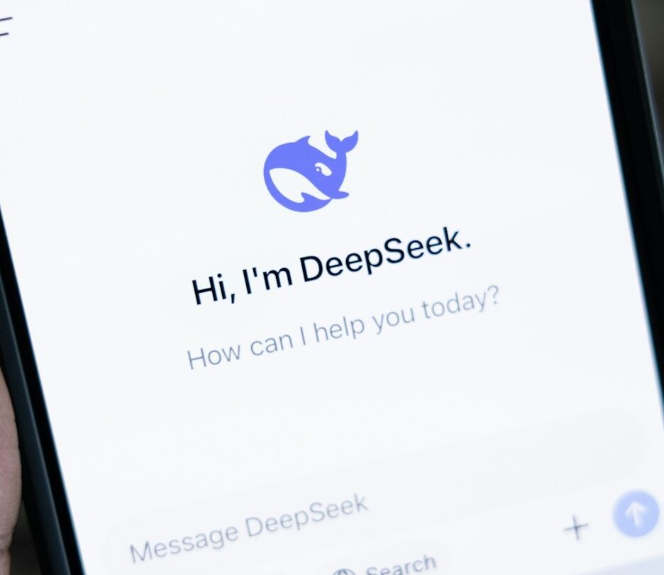 Fotografia em cores de um celular na mão de uma pessoa; o aplicativo aberto no celular é o DeepSeek.